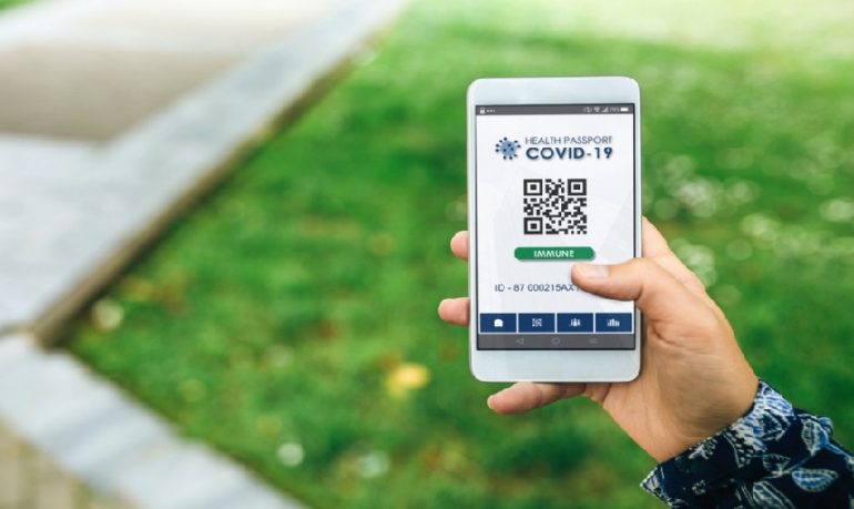 Una mano che tiene un cellulare e mostra un codice qrcode e uno sfondo sfocato di un prato