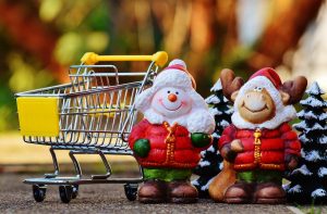 Un'immagine dedicata ai consumi di natale. Ritrae un piccolissimo carrello giocattolo e due statue natalizie